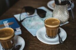 A table with coffee cups and travel books on it