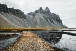 man walking towards Vestrahorn mountain near the beach