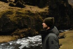 person standing beside Kvernufoss waterfall